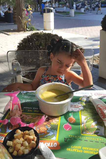 A young girl frowns over a bowl of soup in Varna Bulgaria
