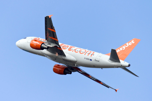 An EasyJet orange and white plane in the air against a blue sky.