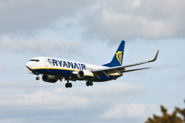 A RyanAir plane with wheels down comes in for a landing.