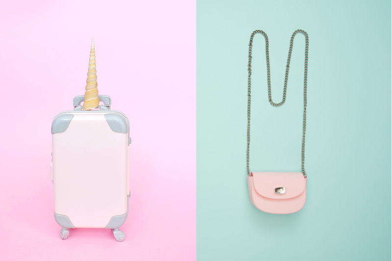 A pink unicorn suitcase on the left, a pink purse on the right.