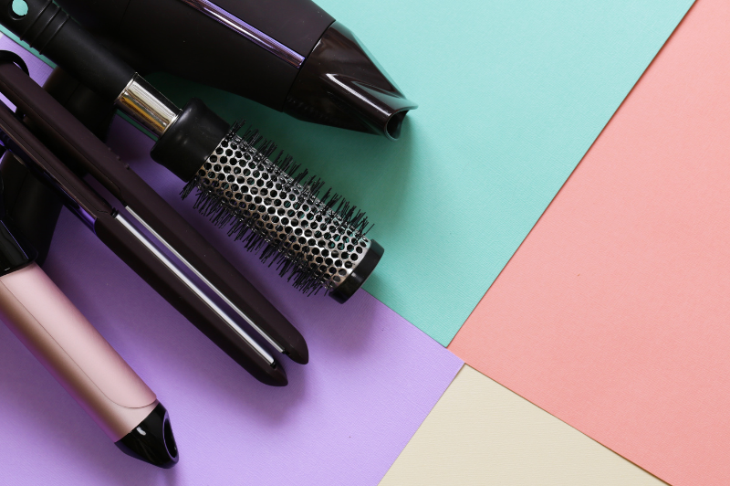 a color block background with hair styling tools laying out.