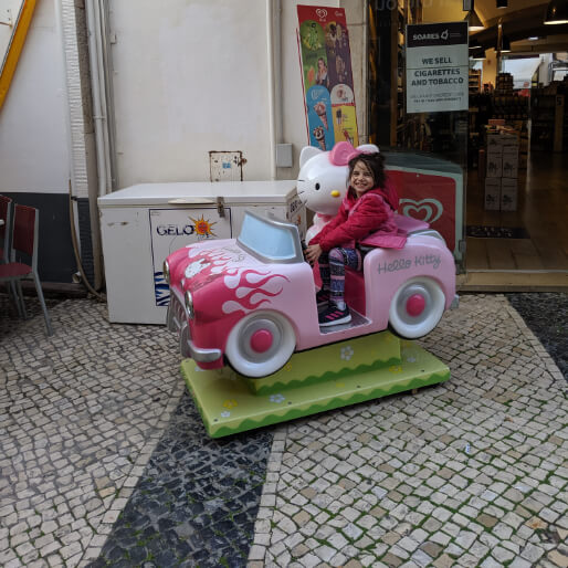 A girl happily rides a coin operated Hello Kitty car in Lagos Portugal