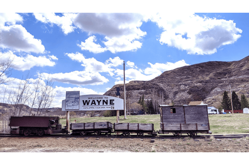 The sign for Wayne Alberta which is mounted to the top of antique coal train cars