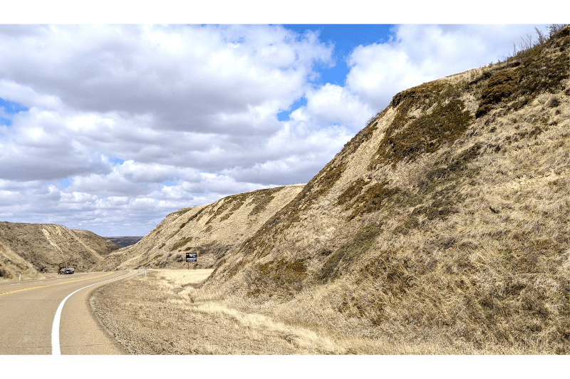 A few grassy hills along a winding road that leads into the Drumheller Valley