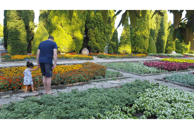 A man and his daughter walk through a colourful garden at Balchik Palace, Bulgaria