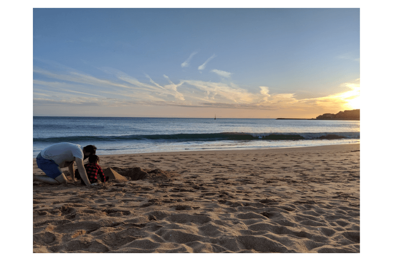 A man and daughter dig on the beach at sunset in Albufeira Portugal