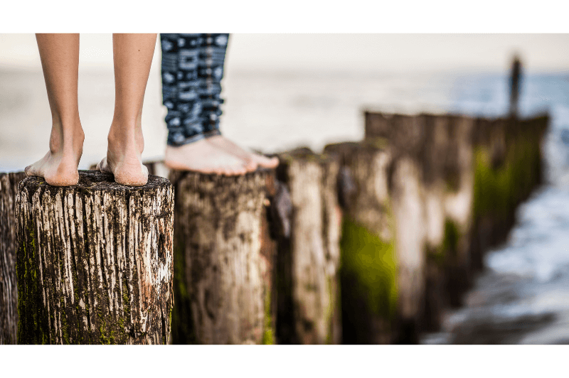 Two pairs of feet standing on posts in the water of a bay in the Oregon