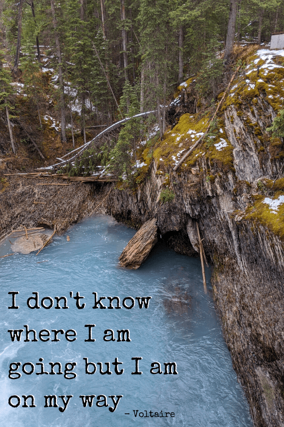 A blue green pool beside a rocky ledge in the forest. Quote reads "I don't know where I am going, but I am on my way." - Voltaire