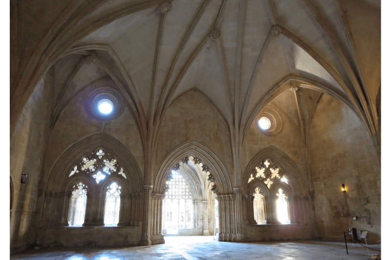 Inside the domed roof of the gothic monastery at Batalha Portugal. Intricate windows look out into the bright light outside.