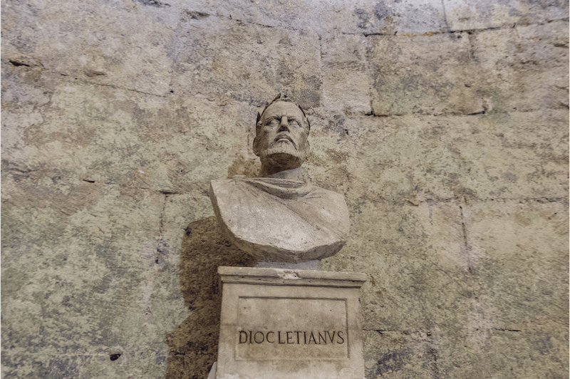 A bust statue of the Emperor Diocletian who ruled Serdica, in front of a stone wall.