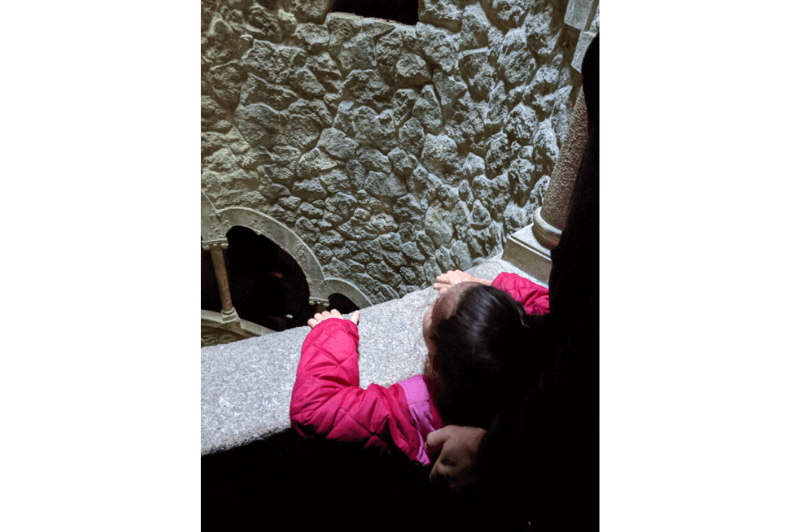 A young girl stops in the spiral staircase of the initiation well at Quinta da Regaleira to look up to the top