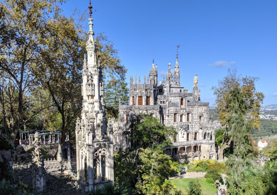 The gothic manor of Quinta da Regaleira from a hill above on the property. The stone manueline gothic architecture is spectacular amongst the surrounding trees on the outskirts of Sintra Portugal
