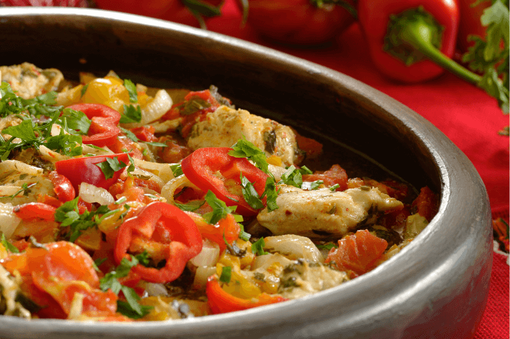 Bulgarian gyuvetch - A mix of tomatoes, peppers, and other ingredients in a clay baking pot.