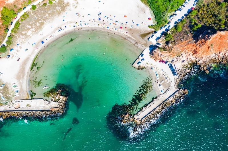 Bolata Beach - A white sand semi circle from above with blue-green water in it
