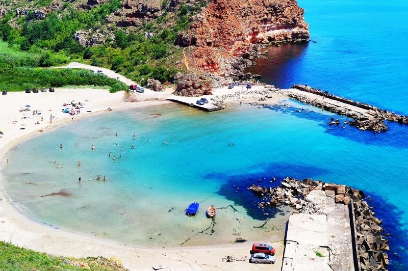 An image of a horseshoe shaped white sand beach in Bolata Bay Bulgaria, with turquoise water and red cliffs surrounding it.