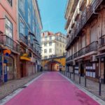 A picture from street level of Rua Nova do Carvalho - Lisbon's pink street - stretching though colorful historic buildings in Lisbon's city center.