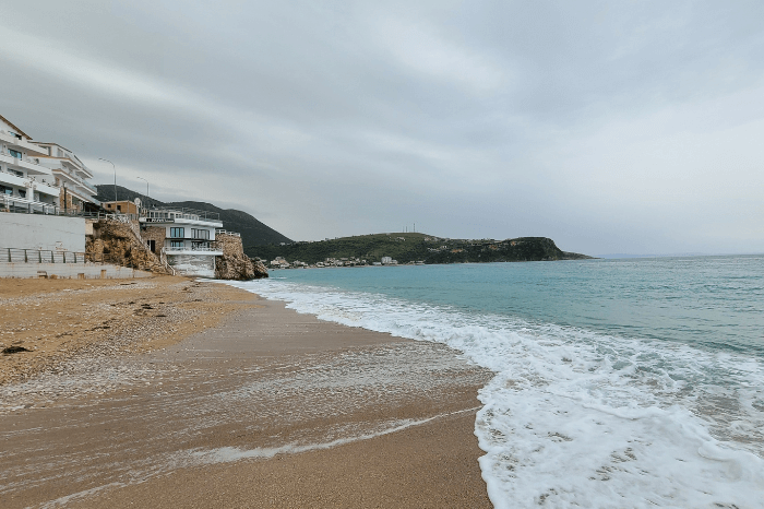 The beach at Himara on a cloudy day. A wide stretch of sand with turquoise waters