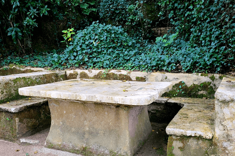 a hill of rolling ivy behind a carved stone booth and table.