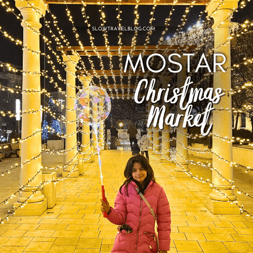 Mostar christmas market light tunnel with a girl standing inside in a pink coat, holding a clear balloon